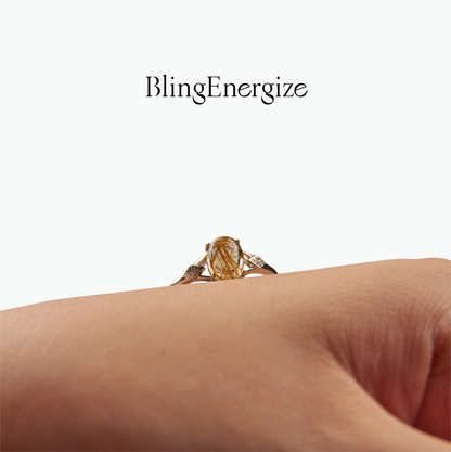 Gold ring with a large gemstone on a person's finger, branded 'BlingEnergize'.
